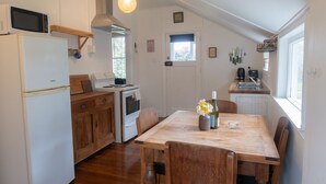 Een keuken met houten kastjes, een witte koelkast, een magnetron, een fornuis en een eettafel met stoelen.