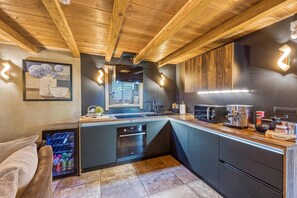A modern kitchen with wooden ceiling beams, a built-in oven, and a coffee machine. - Swan River House with Sauna & Jacuzzi, Lasinja, Croatia (Lasinja)