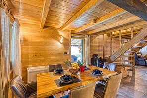 A wooden dining area with a table set for four, a sofa, and a staircase. - Swan River House with Sauna & Jacuzzi, Lasinja, Croatia (Lasinja)
