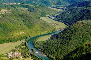 Une vue aérienne d’une vallée traversée par une rivière, entourée de forêts denses et de petits villages.
