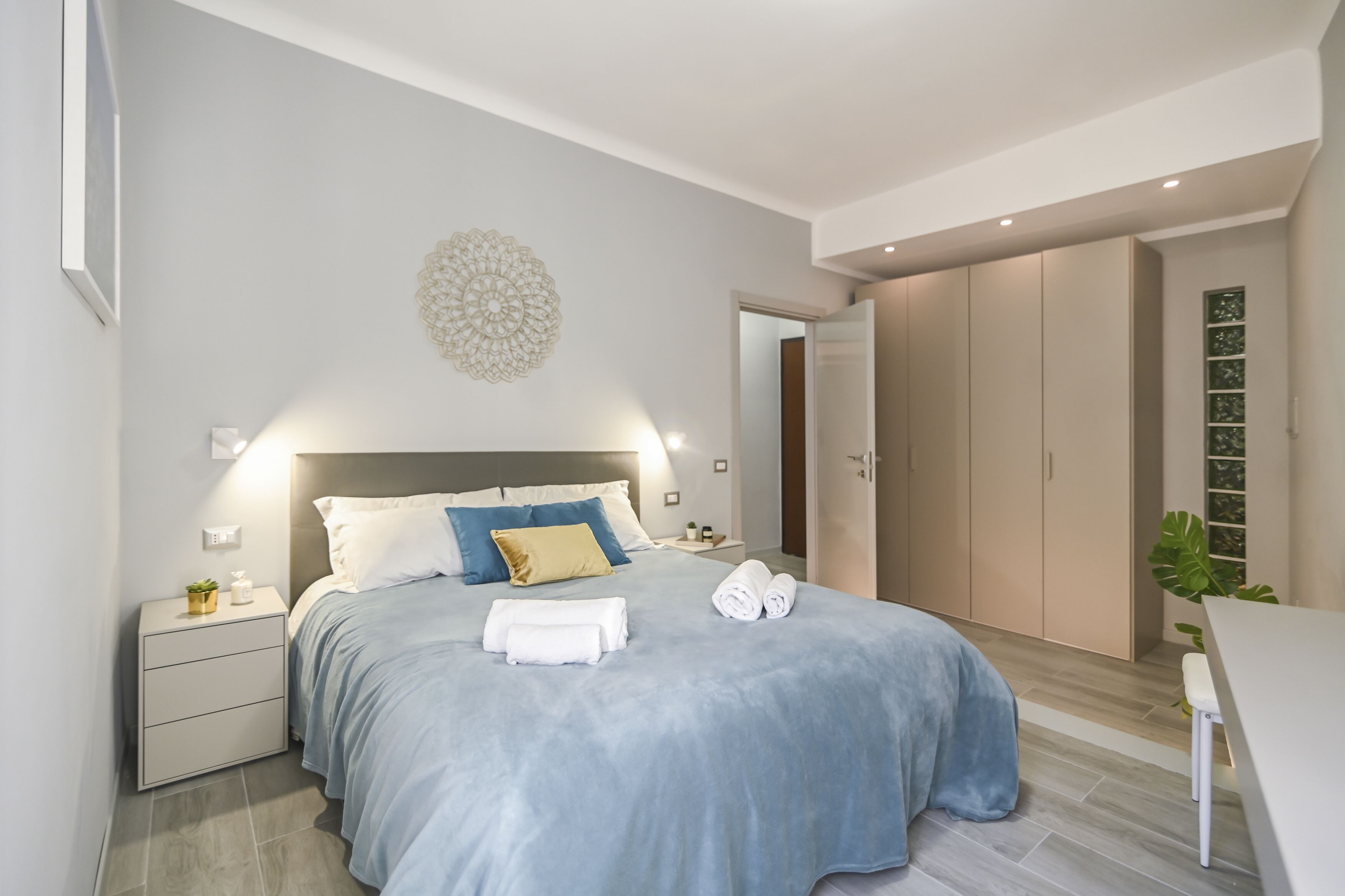 A modern bedroom with a bed, bedside tables, a nightstand, and a wardrobe.