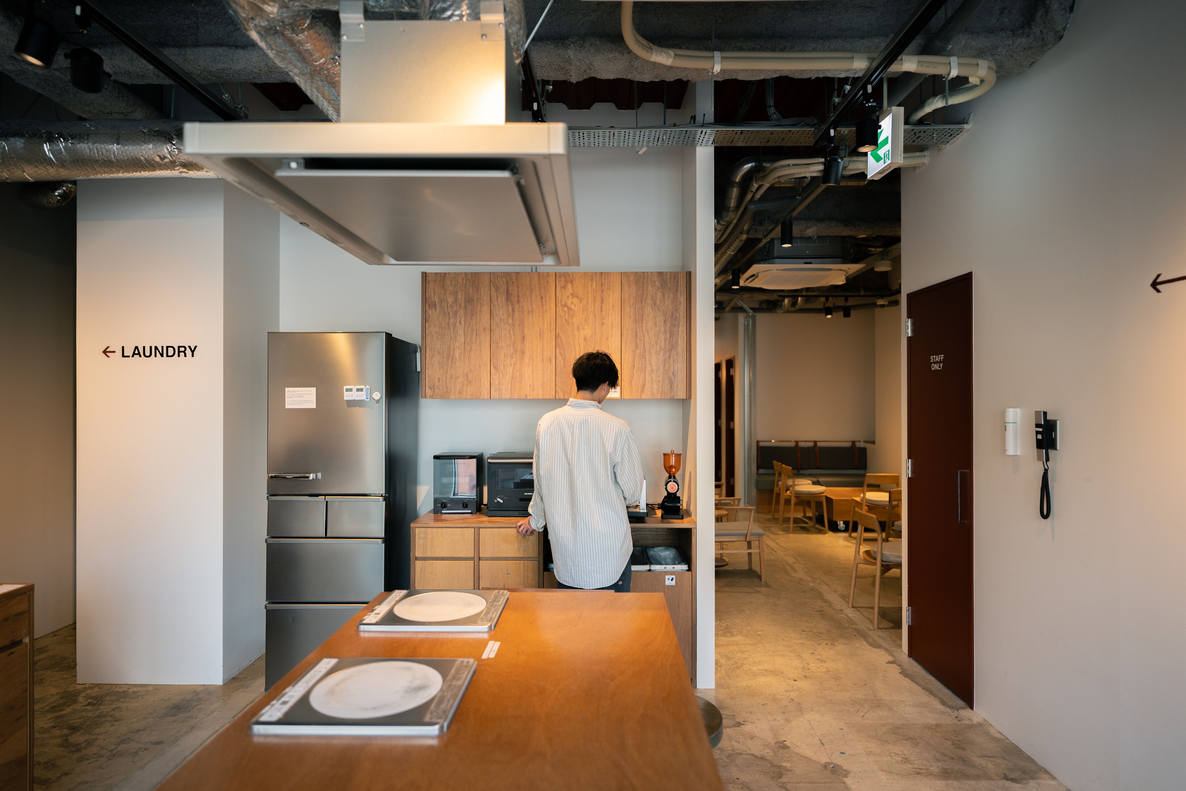 A modern kitchen with stainless steel appliances, a wooden cabinet, and a person standing at the counter.