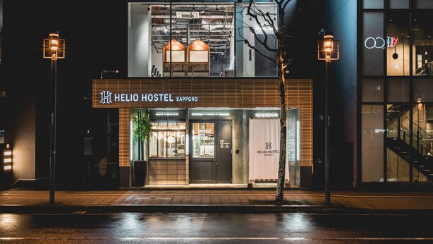 Un ostello moderno con facciata in vetro, un'area 'Take Out' e un ingresso 'Welcome'.