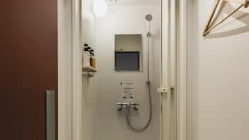 Una ducha moderna con puerta de vidrio, espejo montado y cabezal de ducha manual.