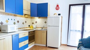 A kitchen with blue and wooden cabinets, a white refrigerator, a microwave, and a sink.