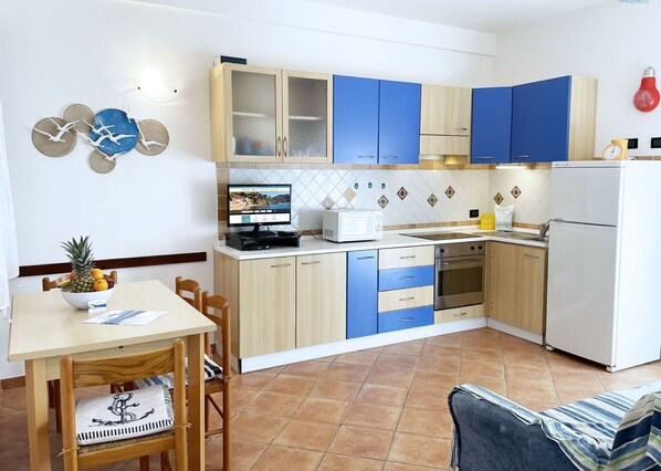 A compact kitchen with a dining area, featuring a microwave, oven, and a small refrigerator.