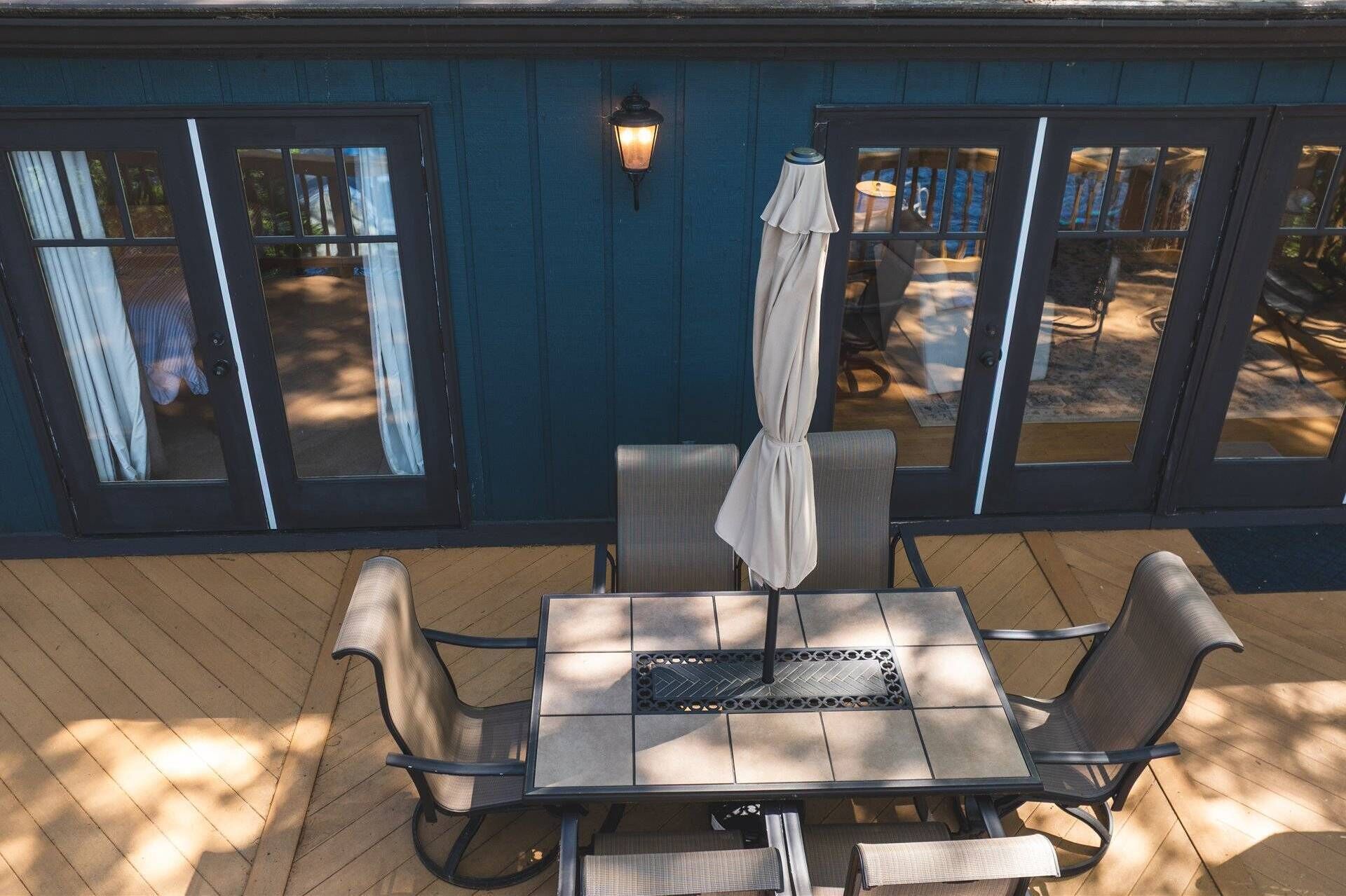 A covered patio with a table and chairs, a hanging umbrella, and a wall-mounted lantern.