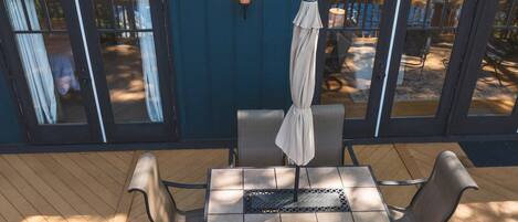 A covered patio with a table and chairs, a hanging umbrella, and a wall-mounted lantern.