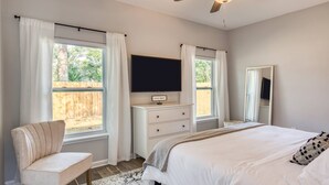 A bedroom with a bed, a chair, a TV, a dresser, and a ceiling fan. - Fire pit, Pet Friendly, Only 1 Mile to Beach, 4 Miles to Historic Downtown, $300 in Free Tickets! (St. Augustine)