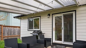 An outdoor patio with wicker furniture, a grill, and a glass door leading to a covered area. - Wonderfully Updated, Pet Friendly, Open Layout, Pool Table, BBQ, Next to Edgefield Golf and Concerts (Troutdale)