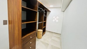 Una stanza con un grande armadio in legno, uno sgabello di legno e un pavimento piastrellato.
