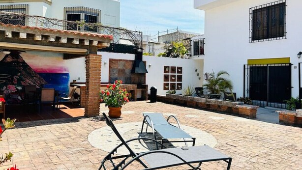 Patio esterno con poltrone relax, barbecue e piante in vaso.