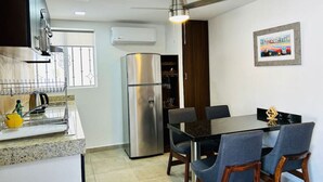 Una cucina moderna con frigorifero in acciaio inossidabile, un tavolo da pranzo con sedie e una ventola a soffitto.