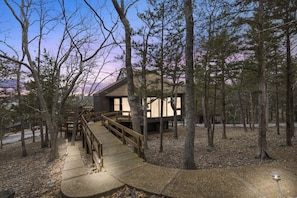 A cabin with a wooden deck and a staircase leading to the entrance.