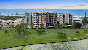 Un hotel de varios pisos con un patio central, rodeado de vegetación y vistas al océano.