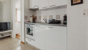 Eine Küche mit weißen Schränken, einem Herd, einer Mikrowelle und einer Kaffeemaschine.