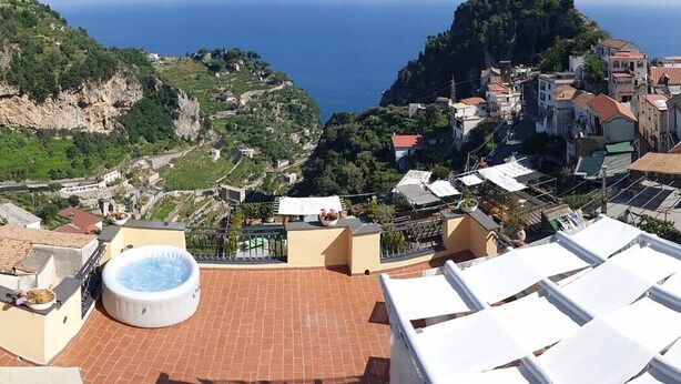 Una terraza en la azotea con jacuzzi, baldosas de terracota y vistas a un pueblo costero.