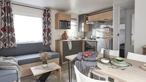 A compact kitchenette with a microwave, stove, and oven. A dining area with a table and chairs is adjacent to the kitchen.