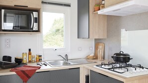 A compact kitchen with a microwave, sink, stove, and a window providing natural light.