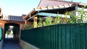 A traditional building with a tiled roof, a green metal fence, and a gate. - Rent House in Residence (Argelès-sur-Mer)