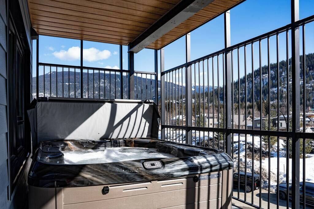 Un jacuzzi en un balcón con vistas a montañas y un estacionamiento.