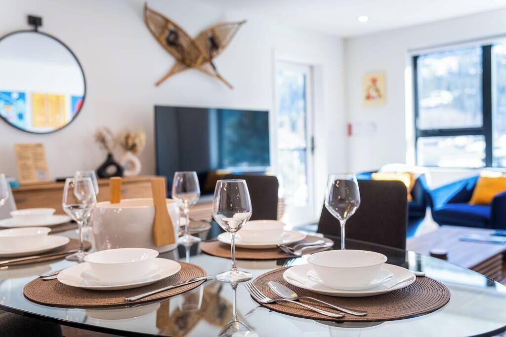 Comedor con mesas redondas, platos blancos y copas de vino preparadas para una comida.