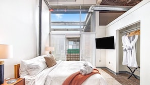 A modern hotel room with a large bed, a TV mounted on the wall, and a view of the outdoors through the window. - Walker's Paradise + Espresso Machine + King Bed (Atlanta)