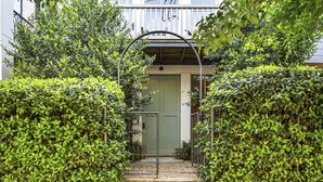 A gated entrance with a metal archway leading to a building with a green door. - Second Floor Balcony | EV Charger |King Bed (Atlanta)