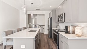 A modern kitchen with a central island, stainless steel appliances, and a seating area with a bench. - Fast Wifi|Downtown EAV| EAV Retreat (Atlanta)