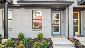 A modern two-story house with a grey brick exterior, a blue door with the number 12, and a small front garden. - Fast Wifi|Downtown EAV| EAV Retreat (Atlanta)