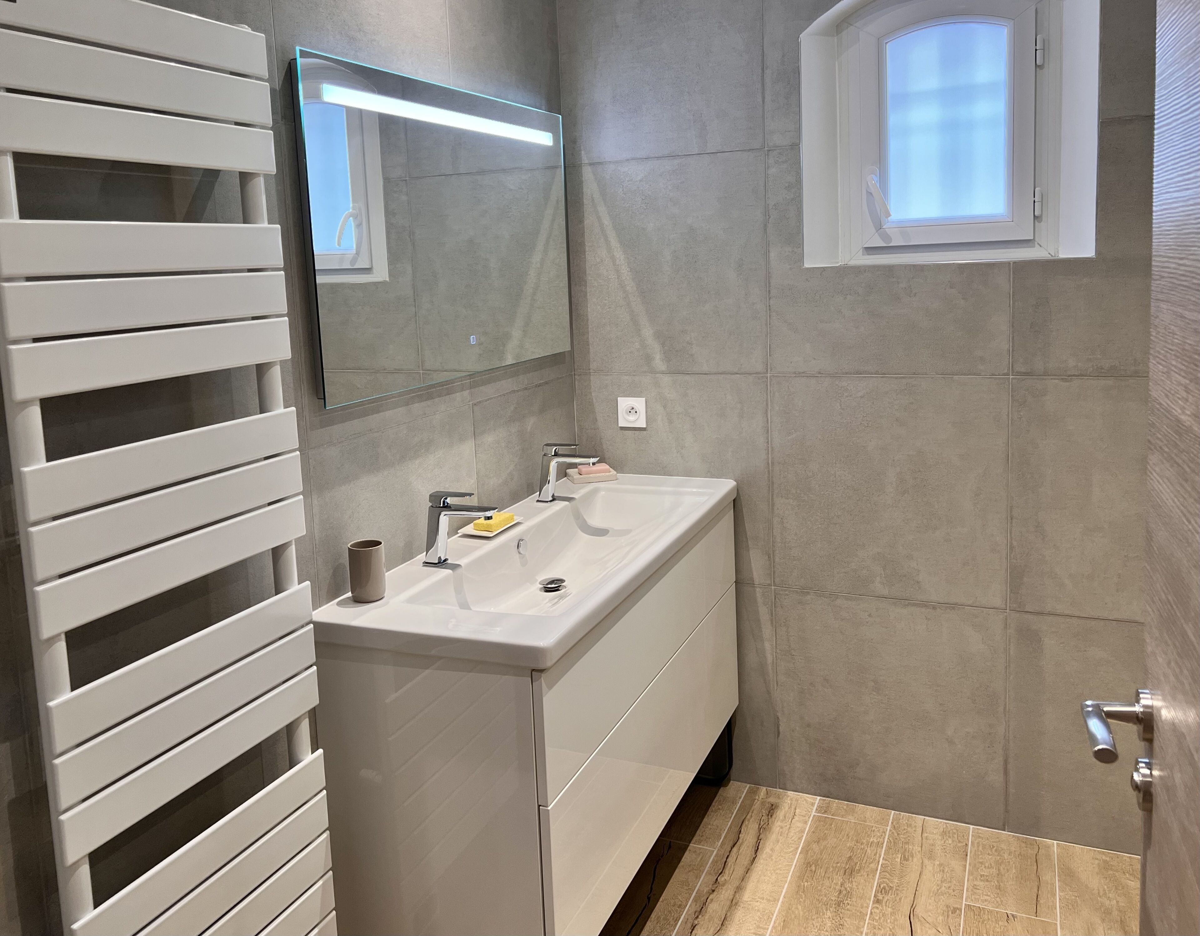 Un bagno con un mobile lavabo bianco, uno specchio e una finestra.