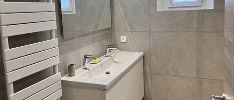 Un bagno con un mobile lavabo bianco, uno specchio e una finestra.