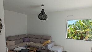 A modern living room with a grey sectional sofa, a small round table, and a hanging light fixture. - House near the city center, beaches and train station. Sea view, terrace. (Bandol)