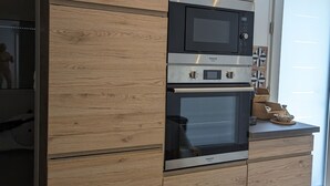 A kitchen with built-in appliances, wooden cabinetry, and a countertop with decorative items. - House near the city center, beaches and train station. Sea view, terrace. (Bandol)