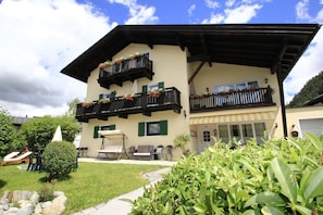 A two-story building with balconies, outdoor seating, and a well-maintained garden.