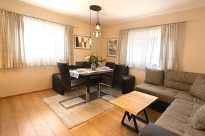 A living room with a dining table, two black chairs, a sofa, and a coffee table.