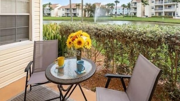 A balcony with a table, chairs, and a vase of sunflowers.