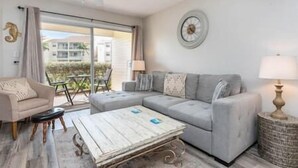 A living room with a grey sofa, a wooden coffee table, a beige armchair, and a lamp.