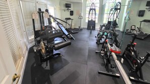A gym with exercise equipment, a treadmill, and a mirrored wall.