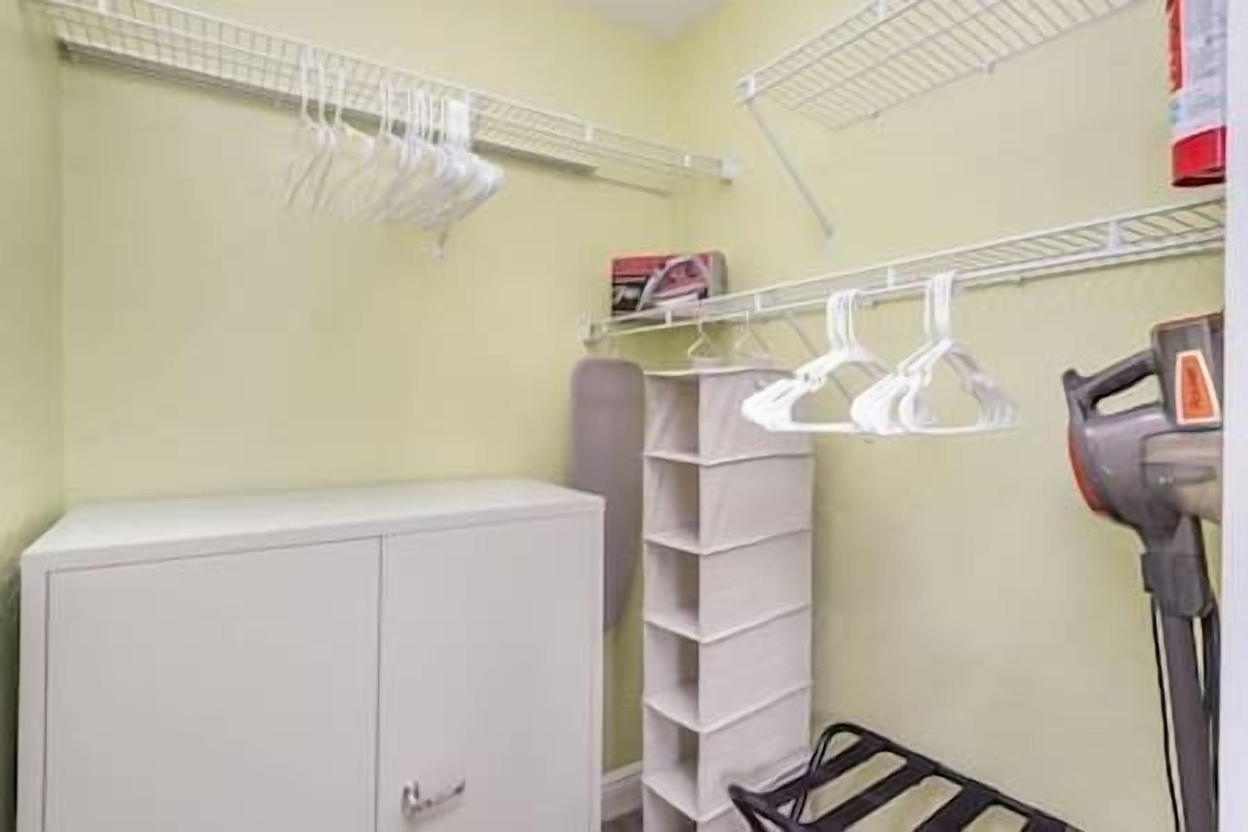 Une salle de bain avec un meuble blanc, un étendoir et un sèche-cheveux.