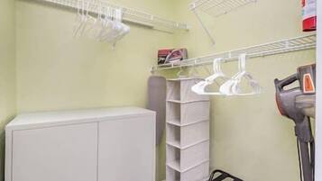 Une salle de bain avec un meuble blanc, un étendoir et un sèche-cheveux.
