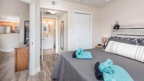 A bedroom with a bed, a nightstand, a ceiling fan, and a door leading to a bathroom.