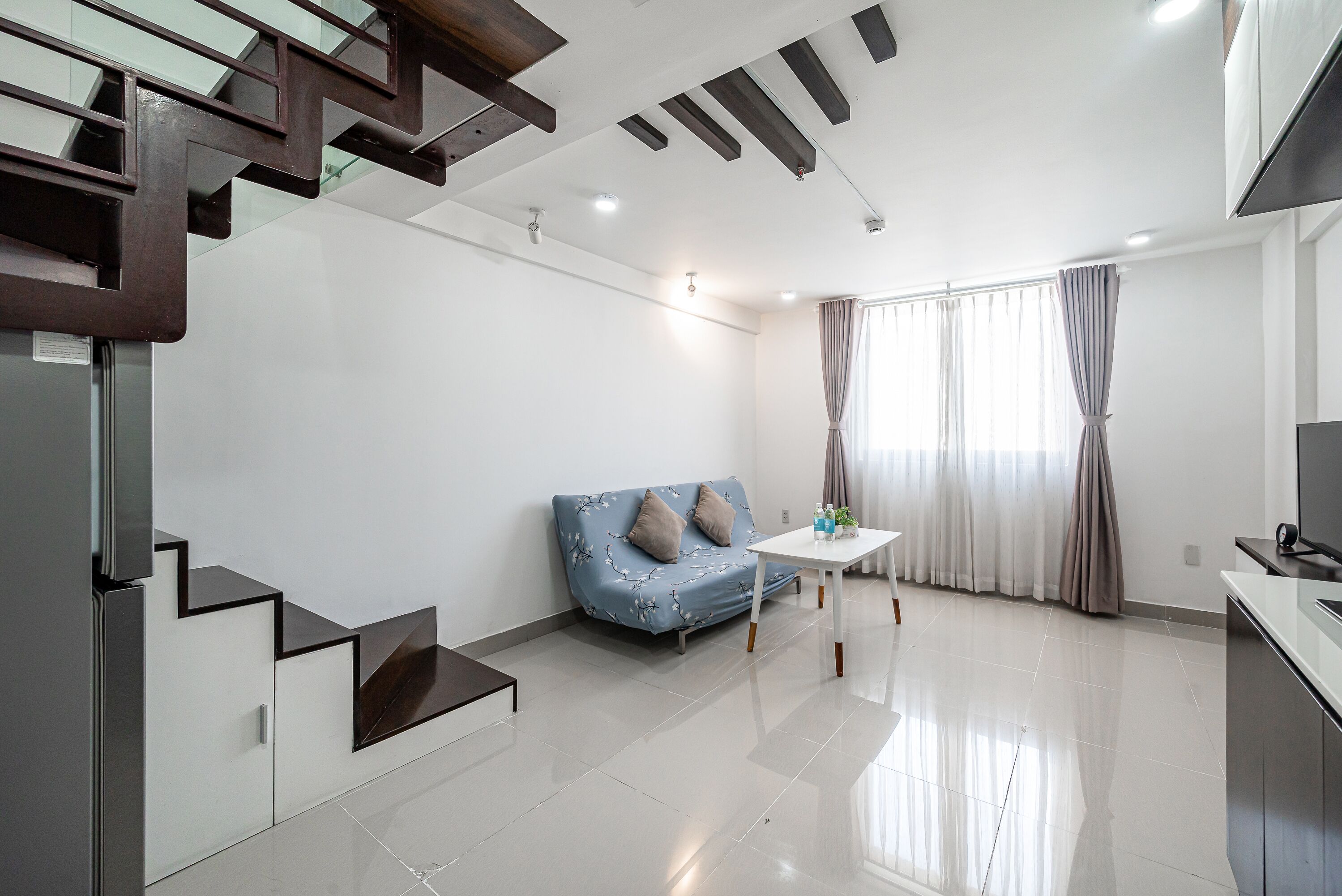 A modern living room with a sofa, a small table, and a staircase.