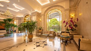 Eine geräumige Lobby mit einer Chandelüster, einer Sitzecke, Topfpflanzen und einem großen Fenster mit Blick.