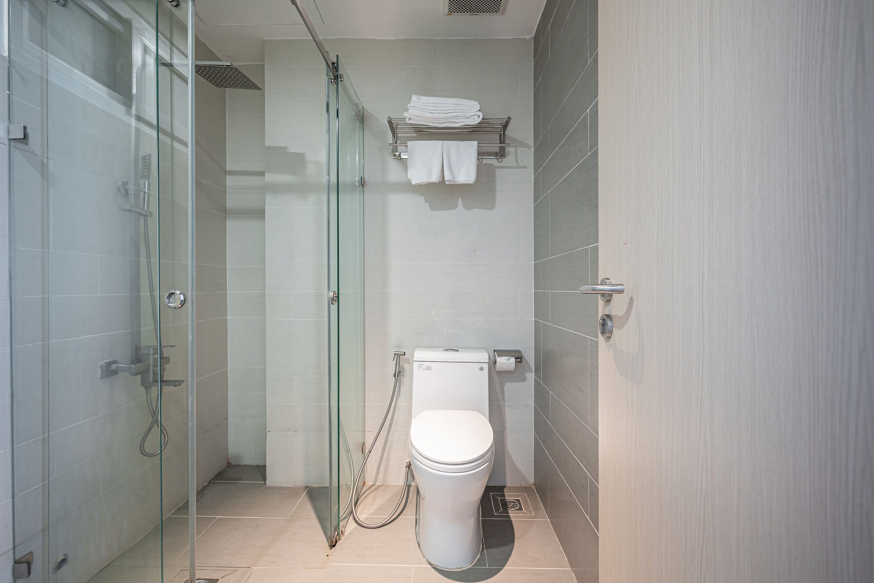 Une salle de bain moderne dotée d’une douche à parois de verre, de toilettes et d’un porte-serviettes.