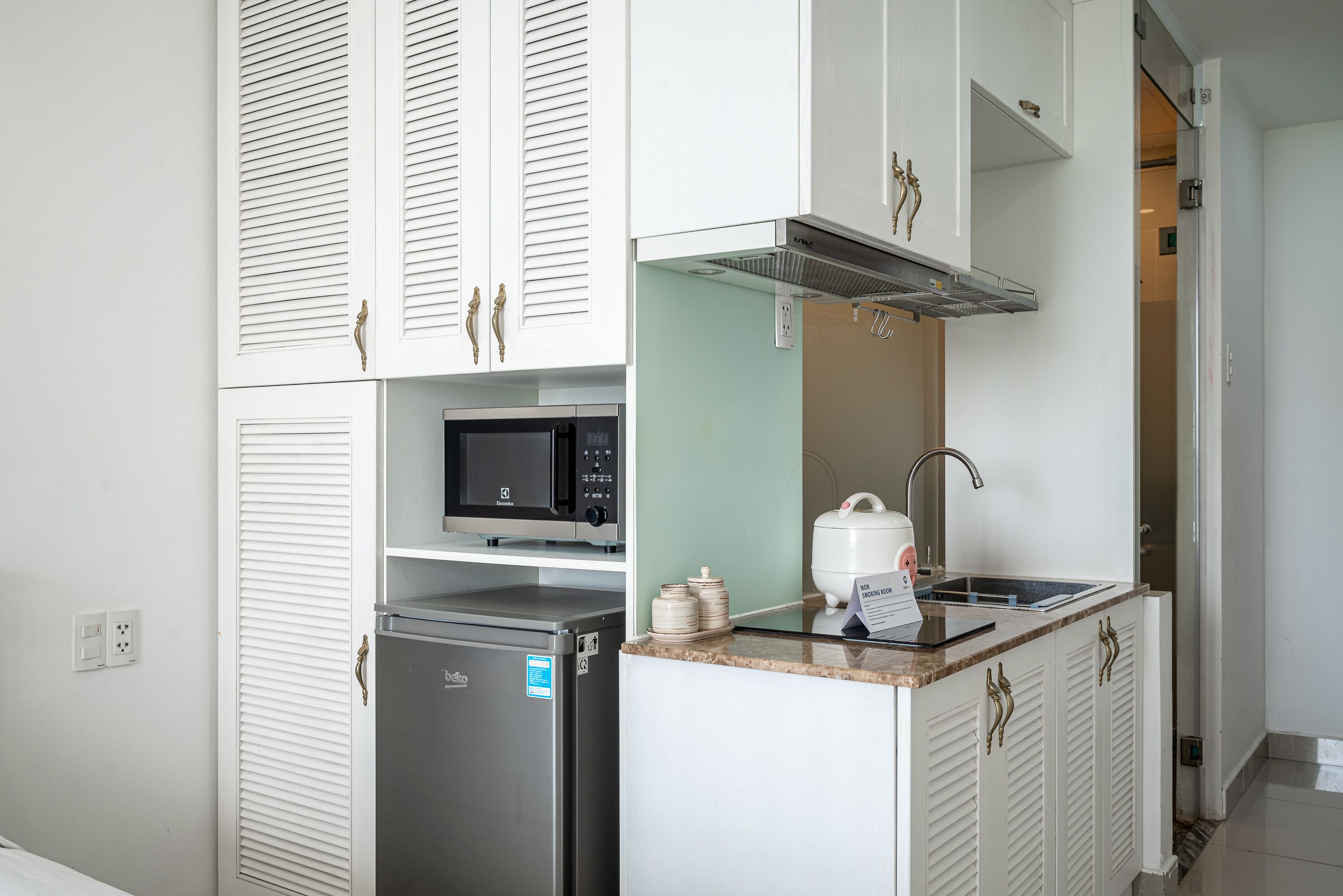 A compact kitchen with a refrigerator, microwave, sink, and a small countertop.
