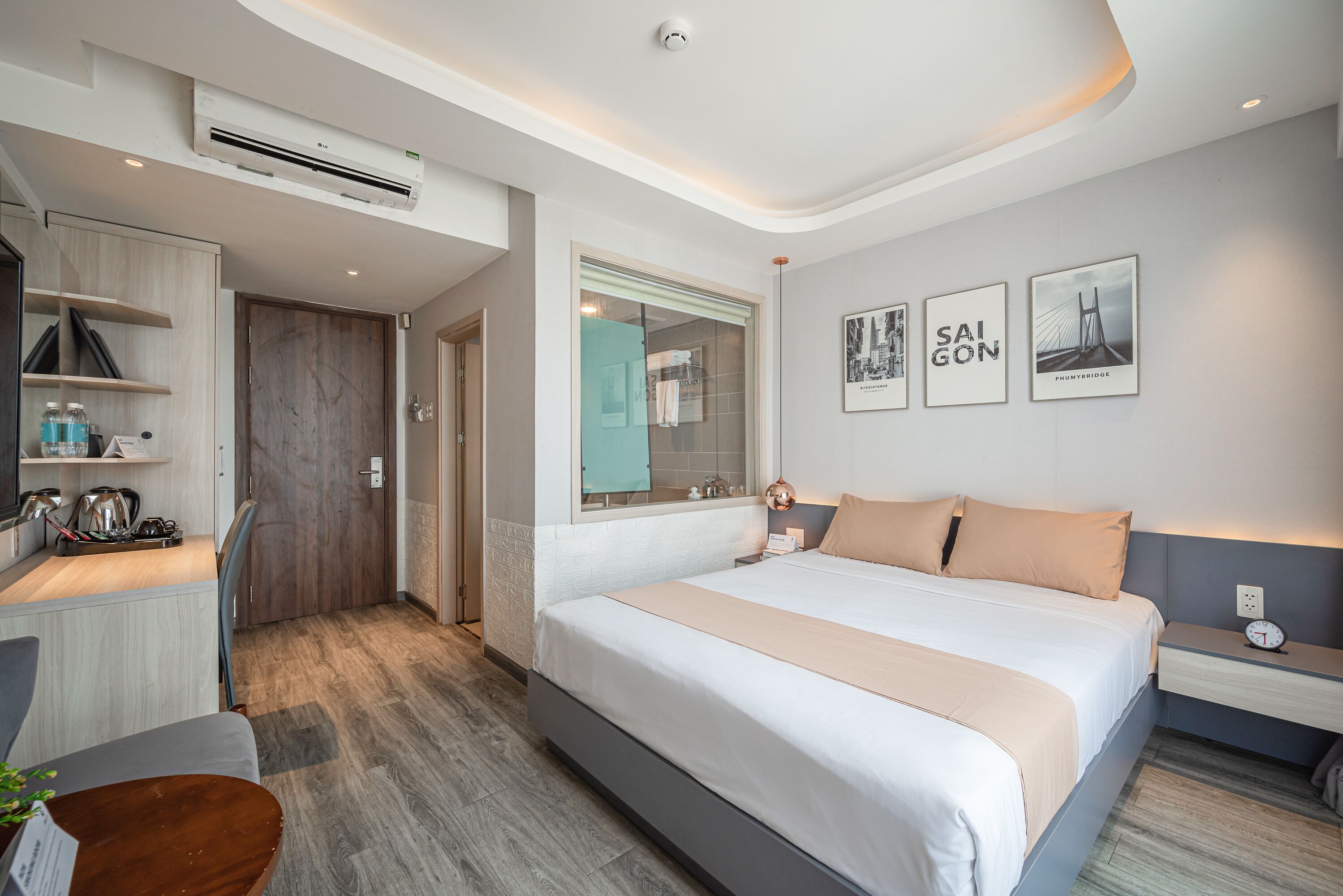 A modern hotel room with a large bed, a desk, and a shower area.