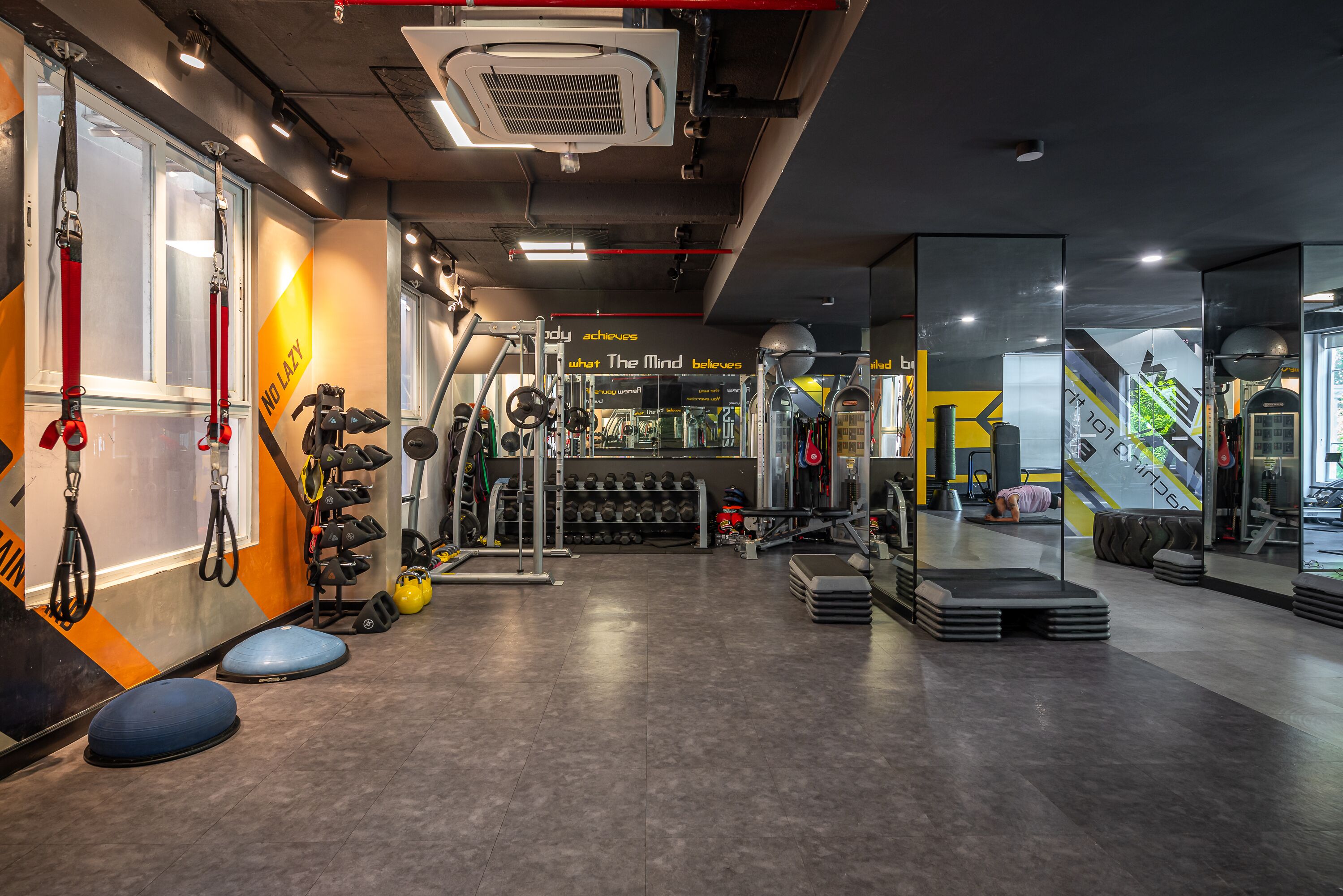 A gym with various exercise equipment, a weight rack, and motivational wall art.