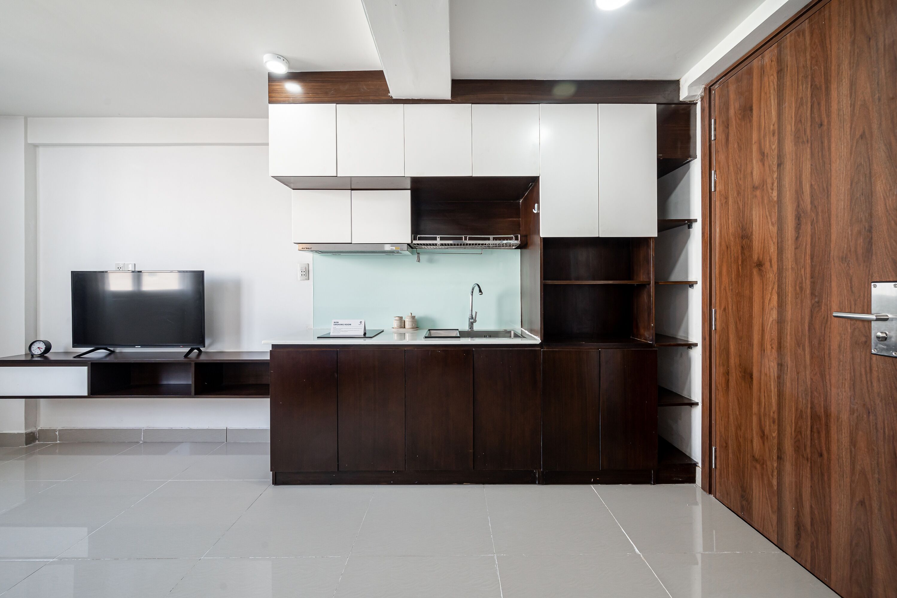 A modern kitchen with a built-in stove, a sink, and a television on a counter.