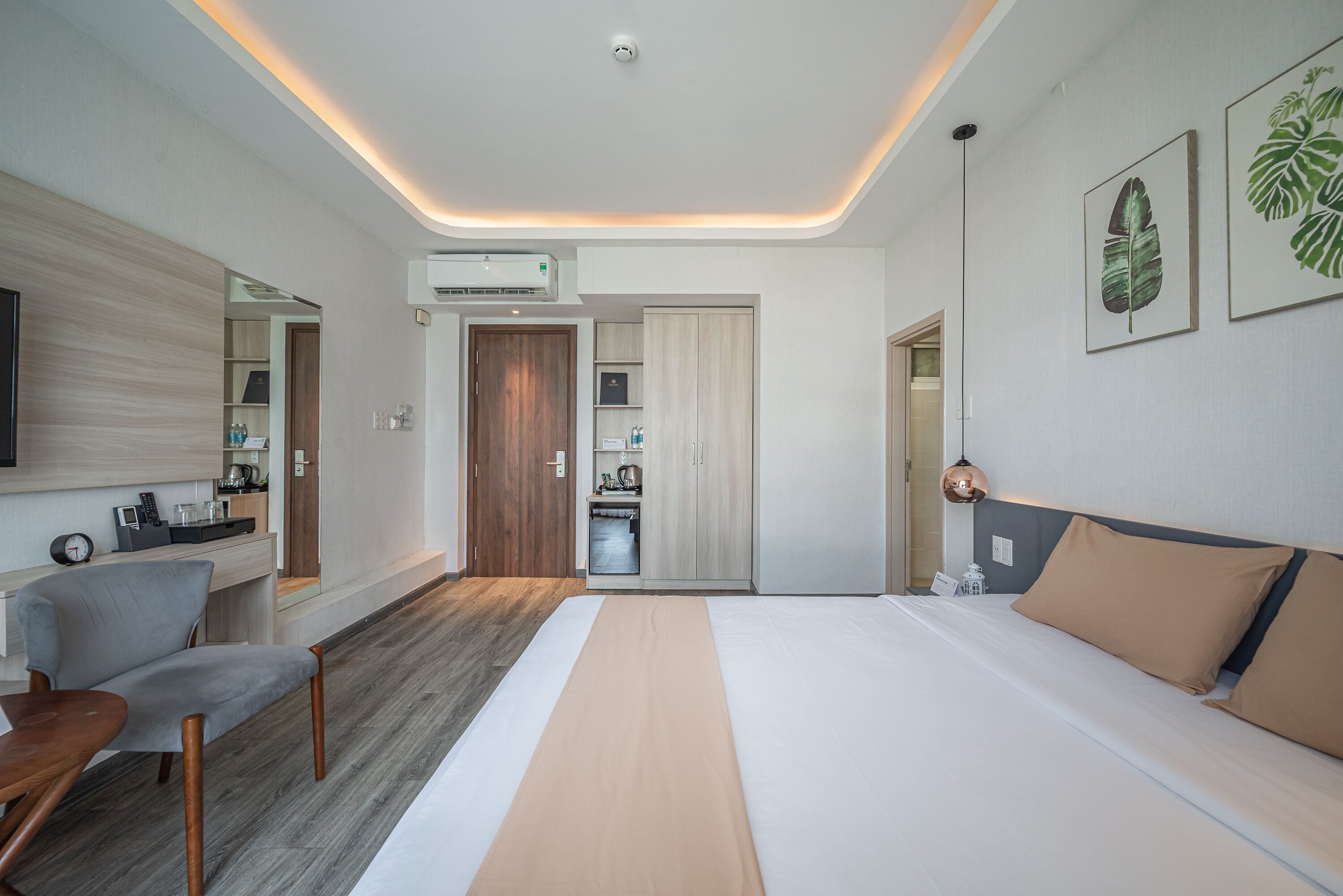 Una habitación de hotel moderna con cama, escritorio, silla y kitchenette.